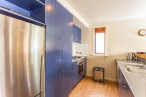 a kitchen with blue cabinets and a stainless steel refrigerator at Absolute Lakeside in Queenstown