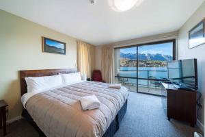 a hotel room with a bed and a desk and a television at Absolute Lakeside in Queenstown