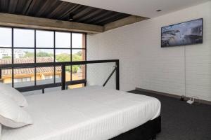 a bedroom with a white bed and a large window at Hermoso Loft en la flora 205 in Cali