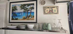 a shelf with dishes and a picture on a wall at Studio Tranquillo avec piscine et salle de sport in Istres