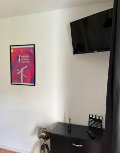 Habitación con TV en una pared blanca y escritorio. en Studio avec piscine près d'Honfleur en Équemauville