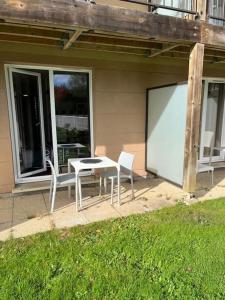 dos sillas y una mesa y una pantalla frente a una casa en Studio avec piscine près d'Honfleur en Équemauville