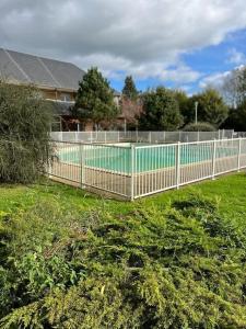 einen Zaun in einem Garten mit Pool in der Unterkunft Studio avec piscine près d'Honfleur in Équemauville