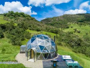 an iglooolithic house on a hill with chairs at Mirror Glamping in Sesquilé