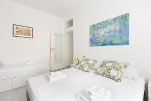 1 dormitorio blanco con 1 cama y una pintura en la pared en Apartment with Balcony -Bisceglie Red Line Subway en Milán