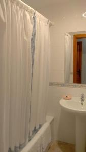 a bathroom with a shower curtain and a sink at Hostal Pineda in Cervera de Pisuerga