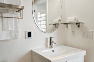 ein weißes Badezimmer mit einem Waschbecken und einem Spiegel in der Unterkunft Boutique Room steps from Downtown Mall Rose Jean - Room 4 in Charlottesville
