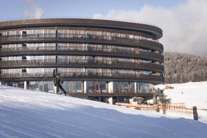 a person on skis in the snow in front of a building at Familienhotel Familiamus in Maranza