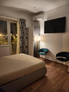 1 dormitorio con 1 cama, 2 sillas y TV en Holding House, en Salerno