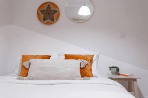 ein weißes Bett mit einem Kissen und einem Spiegel in der Unterkunft 1 Bedroom Suite Yona Hotel in Tel Aviv