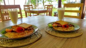 a wooden table with two plates of food and two glasses of milk at Esperanza Beach Mawella in Tangalle