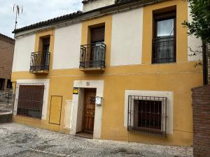 een geel en wit gebouw met ramen en deuren bij Alojamiento Retama Toledo in Toledo
