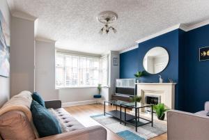 - un salon avec des murs bleus, un canapé et une table dans l'établissement 2 Bedroom House in Chilwell - Perfect for Families and Business, à Beeston