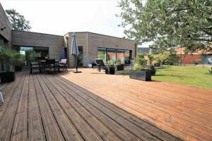 una terraza de madera con mesa y sillas. en Villa d’architecte avec piscine chauffée en Ligny-en-Cambrésis