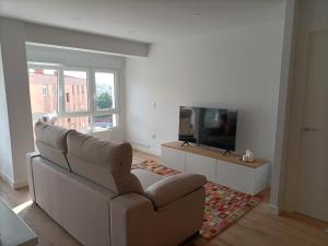 a living room with a couch and a flat screen tv at Precioso Apartamento Nuevo Céntrico en Santander in Santander