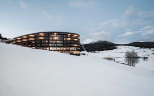 a building sitting on top of a snow covered slope at Familienhotel Familiamus in Maranza