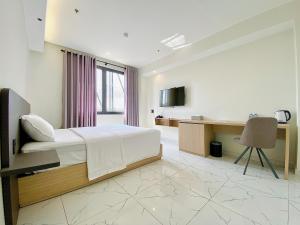 a bedroom with a bed and a desk with a computer at The Luxe Hotel Châu Đốc in Chau Doc