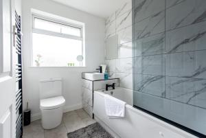 La salle de bains blanche est pourvue d'une baignoire et d'un lavabo. dans l'établissement 2 Bedroom House in Chilwell - Perfect for Families and Business, à Beeston