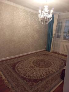 een kamer met een groot tapijt aan een muur met een kroonluchter bij 2-комнатная квартира в центре города in Atıraw