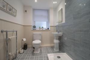 a bathroom with a toilet and a sink and a window at Henry Bell - Cosy 2-bedroom cottage in Helensburgh