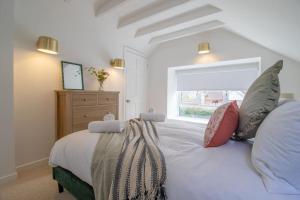 um quarto com uma grande cama branca e uma janela em Henry Bell - Cosy 2-bedroom cottage em Helensburgh