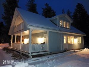 a house with a porch in the snow at night at Cozy house close to SantaVillage in Rovaniemi