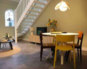 une salle à manger avec une table, des chaises et un escalier dans l'établissement GeinLust B&B De Zonnebloem, à Abcoude