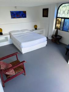 1 dormitorio con 1 cama, 1 silla y ventanas en Finca Jaragual, en La Vega