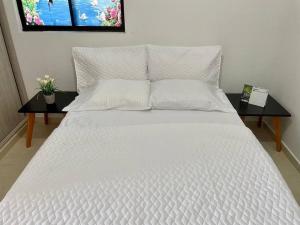 a large bed with white sheets and pillows on it at Reserva Quindiana in La Tebaida