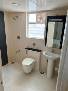 een badkamer met een toilet, een wastafel en een raam bij Serene Living at Marine drive at Kochi in Ernakulam