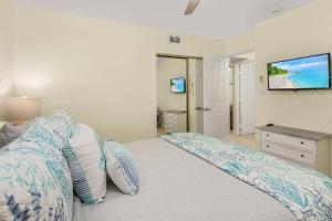 a bedroom with a bed with pillows and a television at Lake Park, 5 O’Clock Somewhere! in Naples