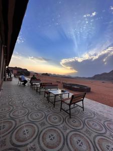 un grupo de mesas y bancos en un patio en Wadi Rum - Deluxe Tent, en Wadi Rum