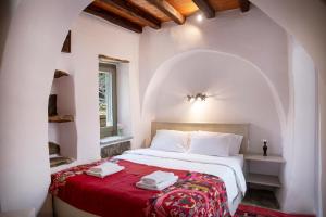 a bedroom with a bed with a red blanket at Under The Linden Tree Tinos in Koumáros