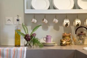 a kitchen counter with cups and plates on a shelf at Under The Linden Tree Tinos in Koumáros