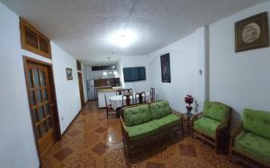 ein Wohnzimmer mit 2 grünen Stühlen und einem Tisch in der Unterkunft Island Suites in Puerto Baquerizo Moreno