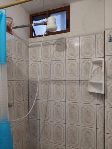 ein Bad mit einem Duschkopf und einer Fliesenwand in der Unterkunft Island Suites in Puerto Baquerizo Moreno