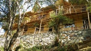 a log cabin with windows and a stone wall at Refugios Salkantay - "StaySoraypampa - Accommodation near Humantay Lake and Salkantay Trek" in Cusco
