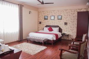 a bedroom with a bed and a desk and a chair at Windermere Inn in Shillong