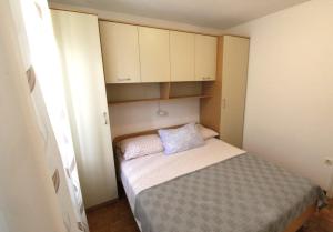 a small bedroom with a bed and white cabinets at Apartments Noel in Zambratija