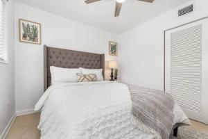 a white bedroom with a large bed with a white comforter at Lovely 2-Bdr w/Patio, Lake Park! in Naples