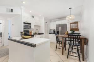a kitchen with white cabinets and a table with chairs at Lovely 2-Bdr w/Patio, Lake Park! in Naples