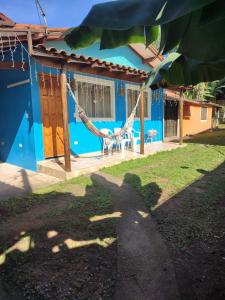 a blue house with a hammock in front of it at Chalé Canto do Galo in Ilhabela