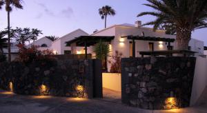 une maison avec une clôture en pierre devant elle dans l'établissement Bungalow GOA Pool view, Playa Roca residence sea front access - Free AC - Wifi, à Costa Teguise