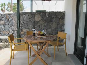 una mesa de madera con sillas y un bol de fruta. en Bungalow GOA Pool view, Playa Roca residence sea front access - Free AC - Wifi en Costa Teguise