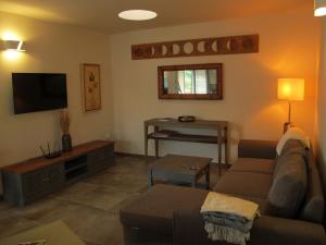 a living room with a couch and a television at Bungalow GOA Pool view, Playa Roca residence sea front access - Free AC - Wifi in Costa Teguise