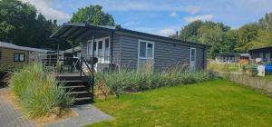 a small house with a black awning in a yard at Ostseecamp Lübecker Bucht Meeresbrise in Scharbeutz