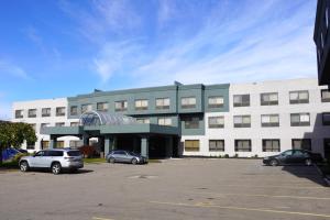 un gran edificio con coches estacionados en un estacionamiento en American Inn & Suites, en Waterford