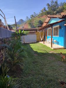a house with a yard with chickens walking in front of it at Chalé Canto do Galo in Ilhabela