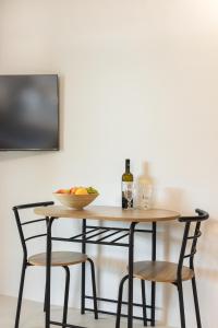 Chariclea Villa في ساموس: طاولة مع كرسيين ووعاء من الفواكه وزجاجة من النبيذ