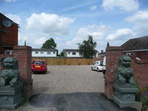 a driveway with two stone statues of foo fists at Beijing Dragon Hotel in Spilsby